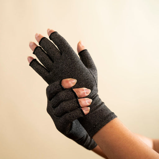 Woman's hands with compression gloves.  Gray compression gloves for carpal tunnel are great hand care products, since they help to improve blood flow and reduce swelling. These compression gloves can also be called compression gloves for arthritis and compression fingerless gloves.